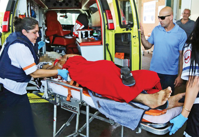 Image of MDA paramedics loading a terror attack victim on a stretcher into ambulance.
